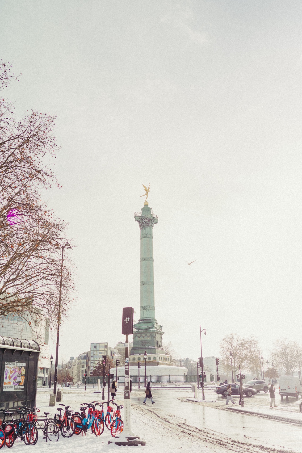 Bastille column in snow with colourful bike-share bikes in foreground