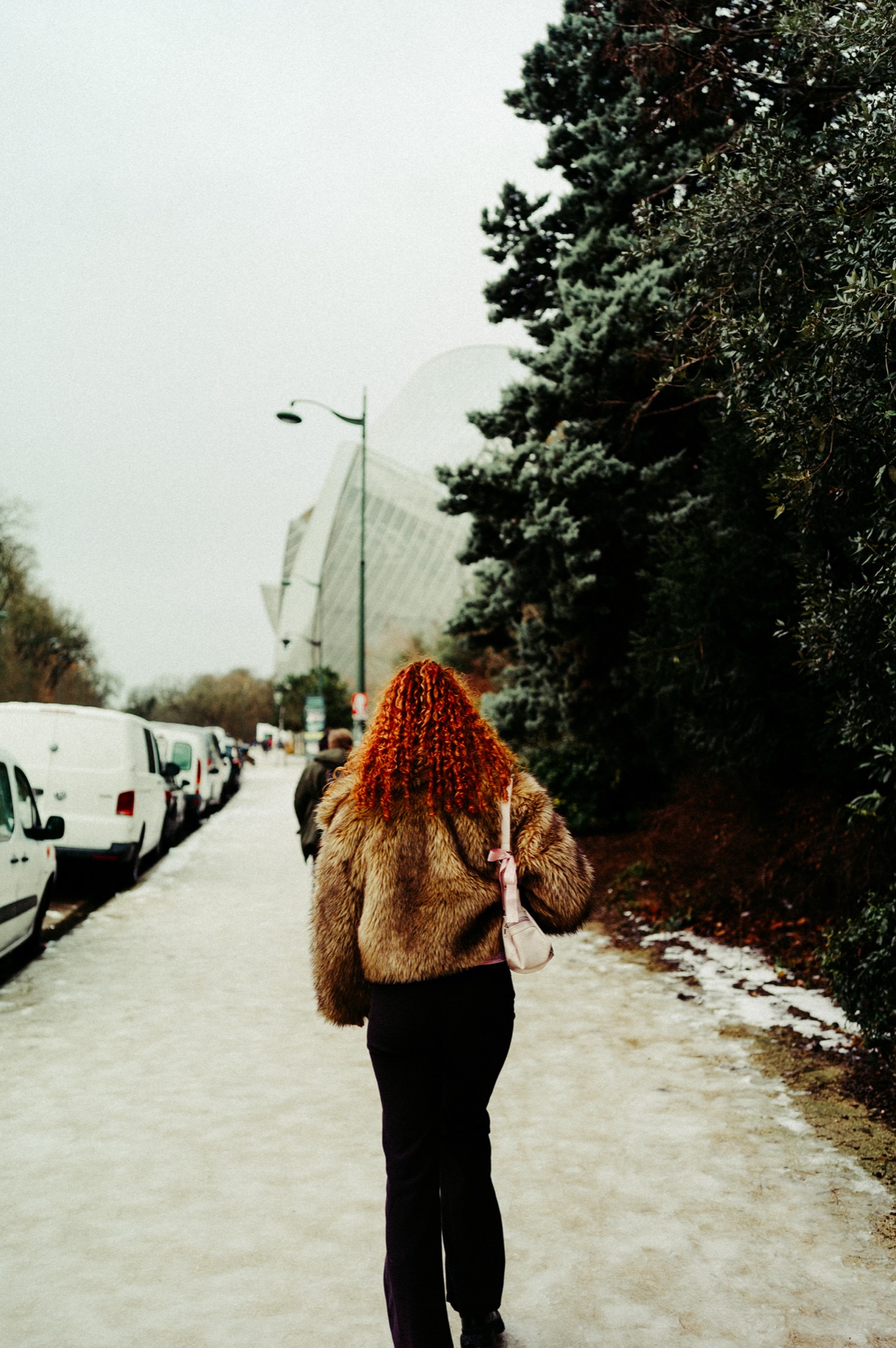 Woman walking toward Fondation Louis Vuitton in snow