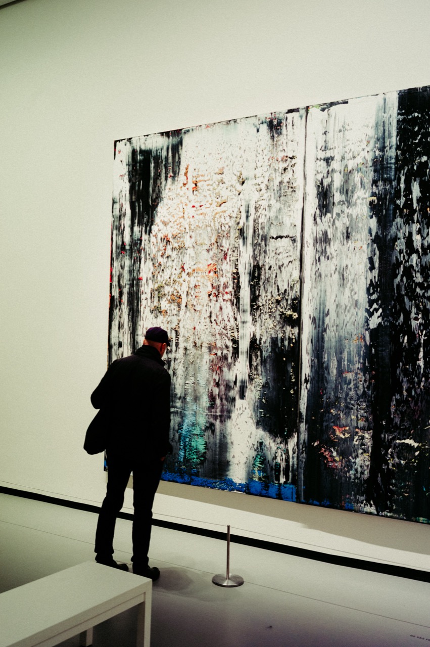 Visitor standing before a large Richter painting